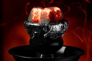 Extreme close-up van twee fel gloeiende shisha-kolen op een met aluminiumfolie bedekte kop, met vonken en een intense rode gloed.